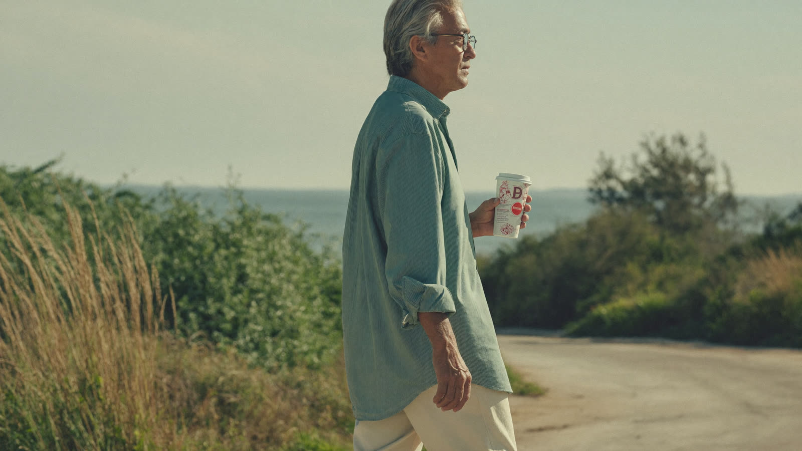 Man in his late forties walking on a sunlit coastal path in the morning