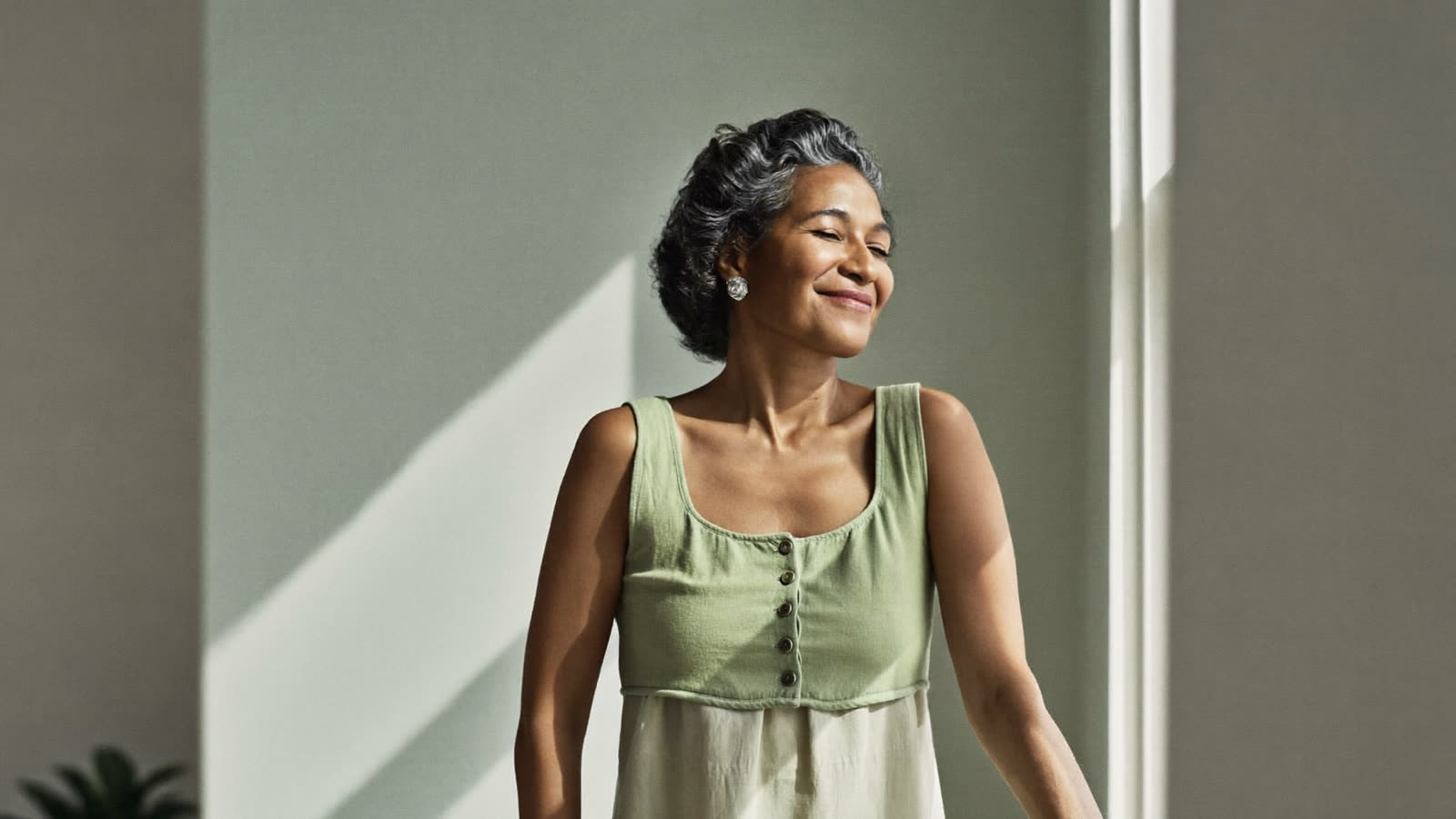 Woman standing at an open window in cool morning air with her eyes closed