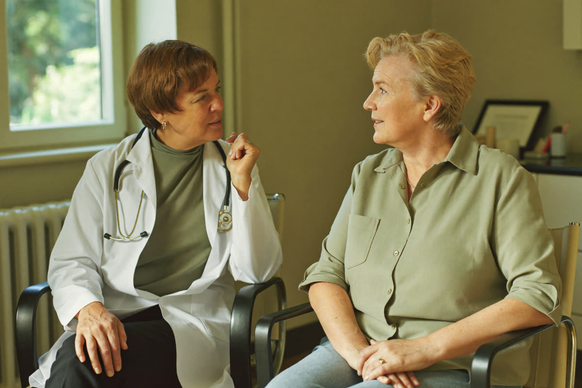 Two women seated in conversation in a sunlit consultation room